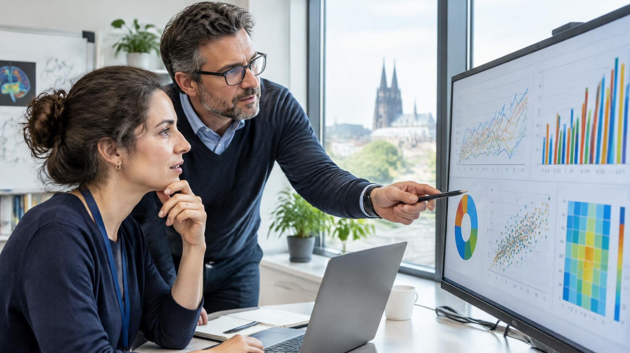 Researchers analyzing data charts on a screen in an office